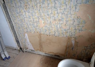 an old wallpapered bathroom wall stripped out for redecorating