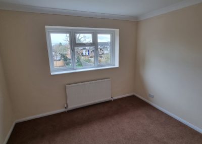 a newly painted small bedroom with 2 white doors, cream walls and mocha carpet