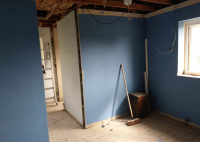 a bedroom renovation with bare ceilings and floors and newly painted dark blue walls