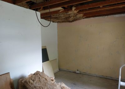 a stripped out room with bare ceiling and walls with hanging wires and fibreglass piles, awaiting decoration
