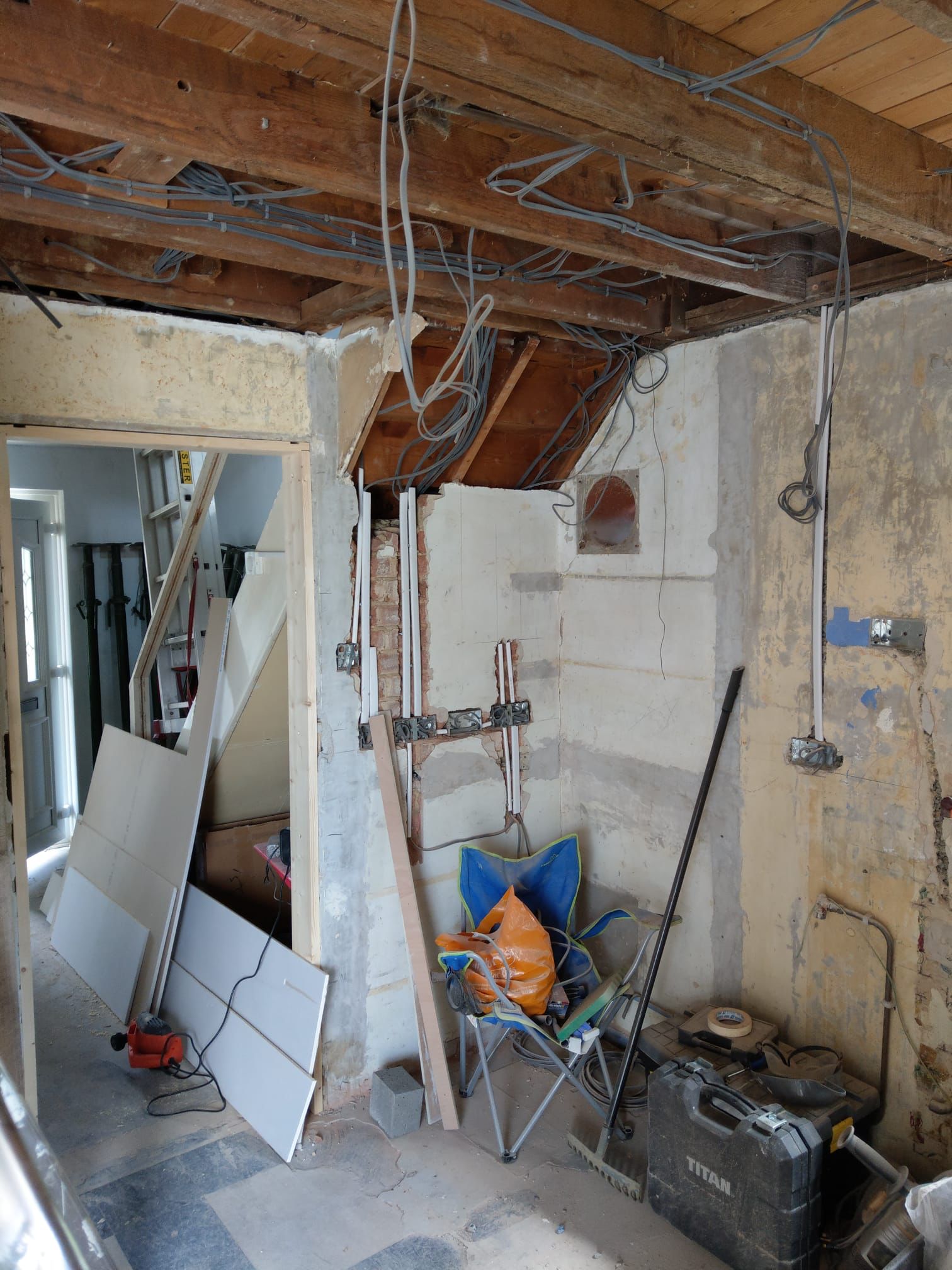 A newly fitted kitchen and hallway with white cupboards, built in oven, wooden worktops and wooden laminate flooring. Olive green paint on the walls.