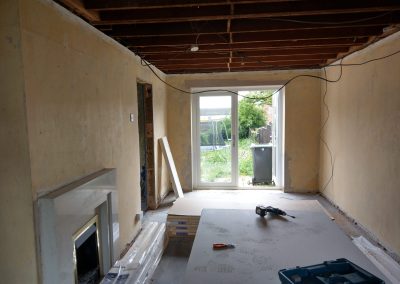 a stripped out living room with bare ceiling and walls and an old fireplace