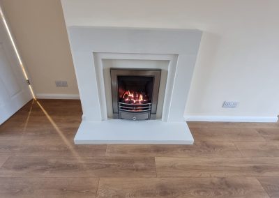 a new fireplace with white surround, light walls and wooden laminate flooring