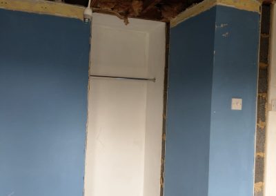 a room stripped out ready for decoration. Old wardrobe space with blue painted wall, bare floorboards and stripped ceiling