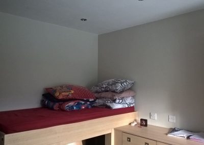 a cabin bunk piled with pillows against grey walls