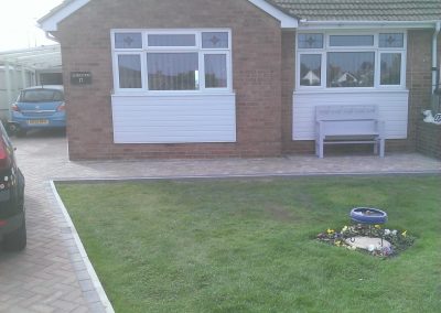 a bungalow with paved driveway and path and a small grass area in front.