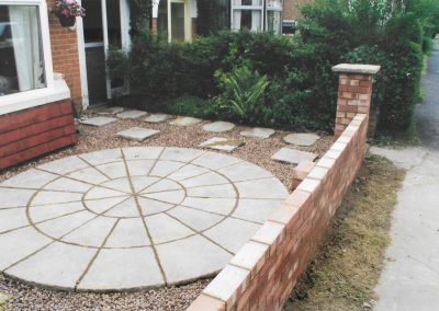 a semi detached house with white bay window and a new paved area and garden brick wall outside
