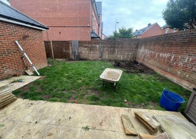 a patch of garden being dug out with large brick walls surrounding.