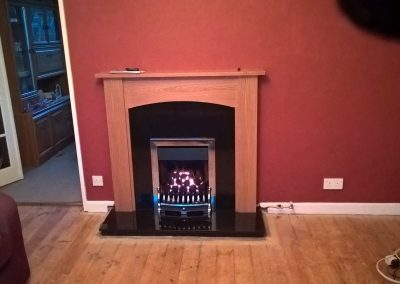 a wooden fireplace surrounding a gas coal effect fire and dark red wall