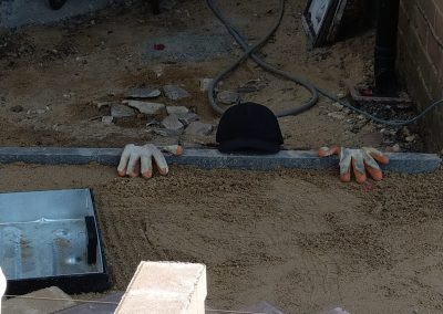a builders area of sand and tools with gloves and hat on floor