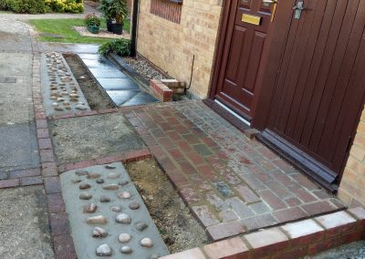 a new front door step area with red brick against a mahogany coloured front door