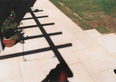 a cream patio with shadows of railings cast onto it.