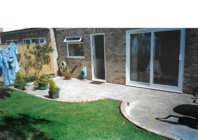 a new patio with 2 circular small brickwall areas looking towards a house with back door and patio doors