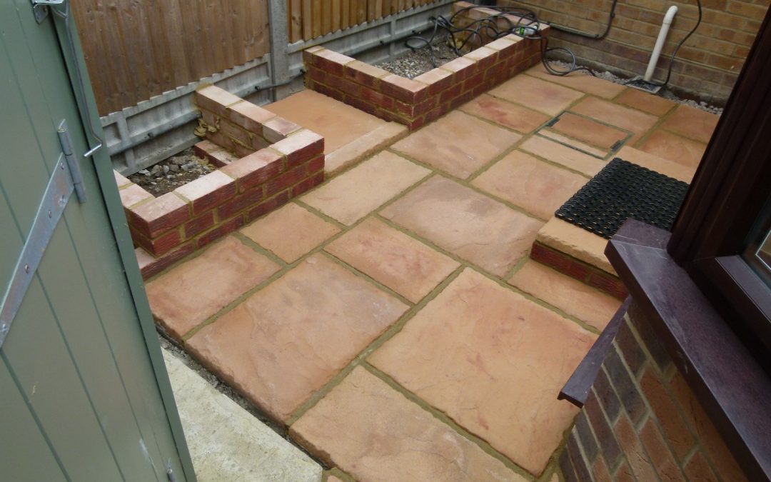 small outdoor paved area with sandstone slabs and two small brickwall areas