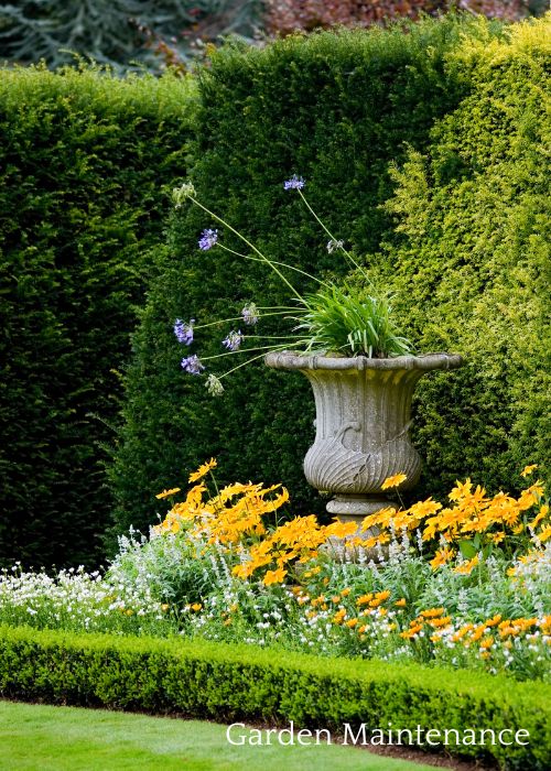 a beautiful large country house surrounded by green lawns and established garden beds with a newly laid paved path up to the door