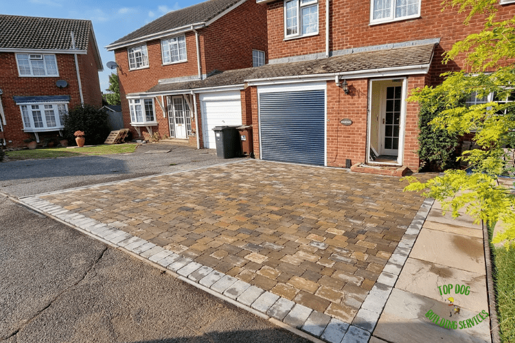 a brick laid driveway in front of blue garage door with paved side path